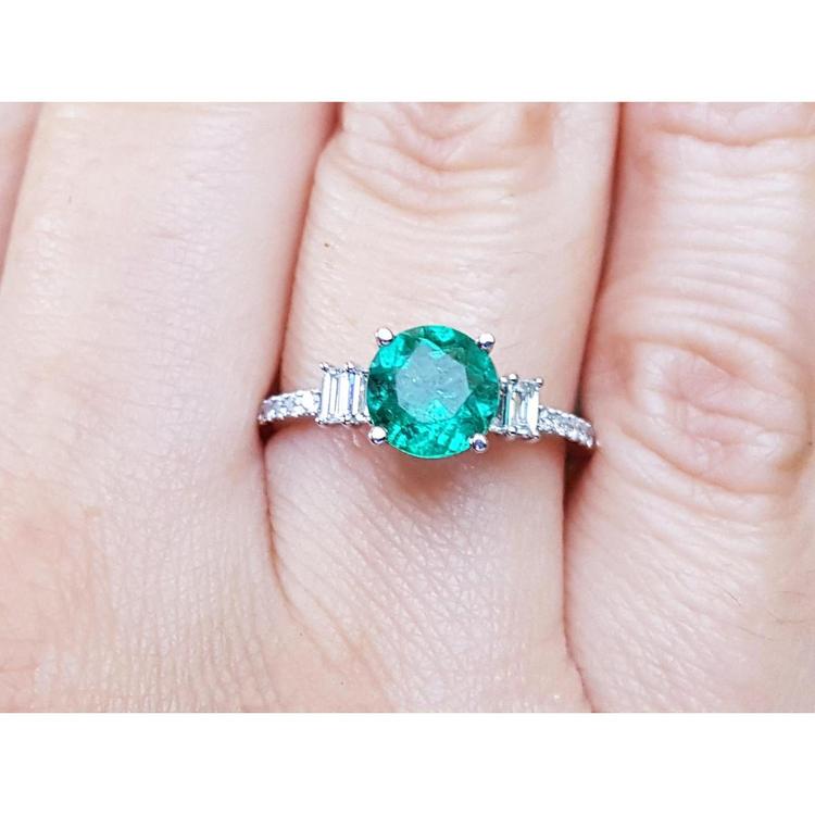 Emerald and baguette side diamonds ring for ladies in 14k white gold on a finger.