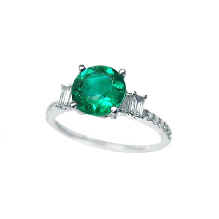 Round cut colombian emerald ring and side baguette diamond accents crafted in 14k white gold for women.