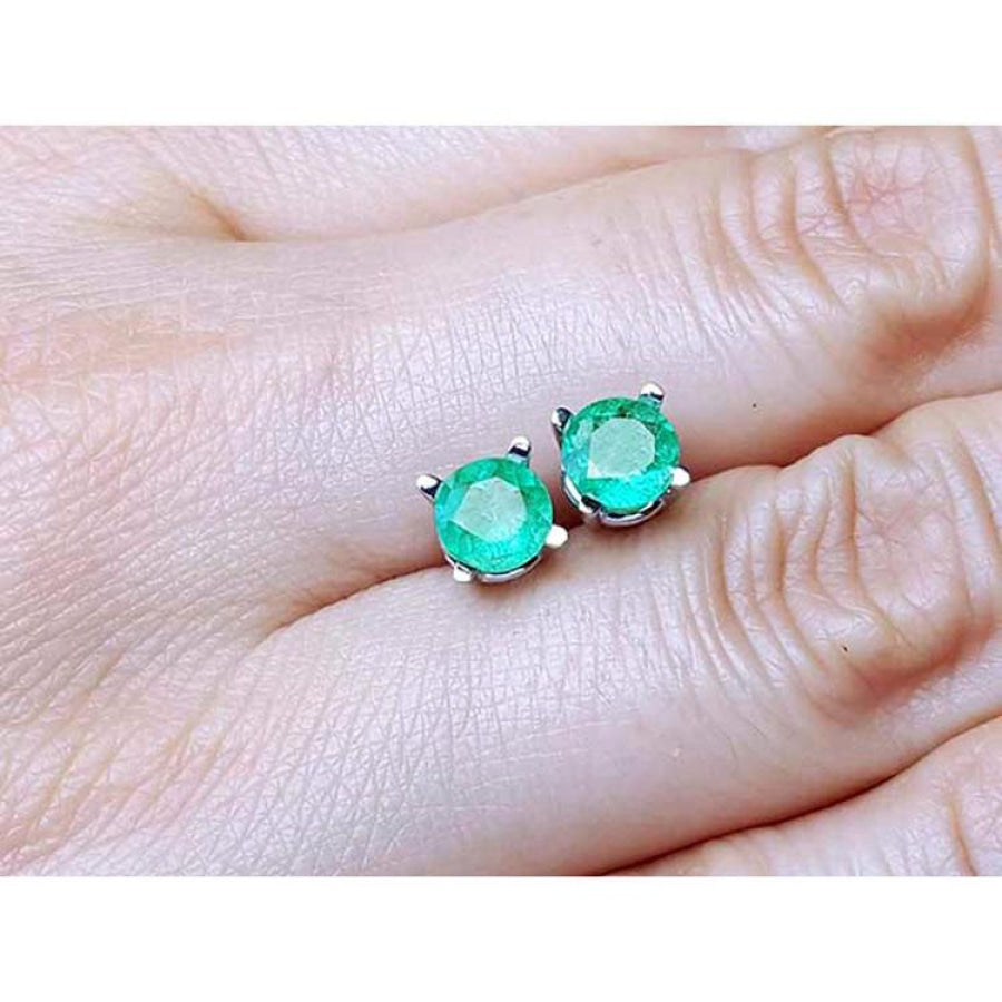 0.89 ct. round Colombian emerald stud earrings in 14k white gold, held on a hand.