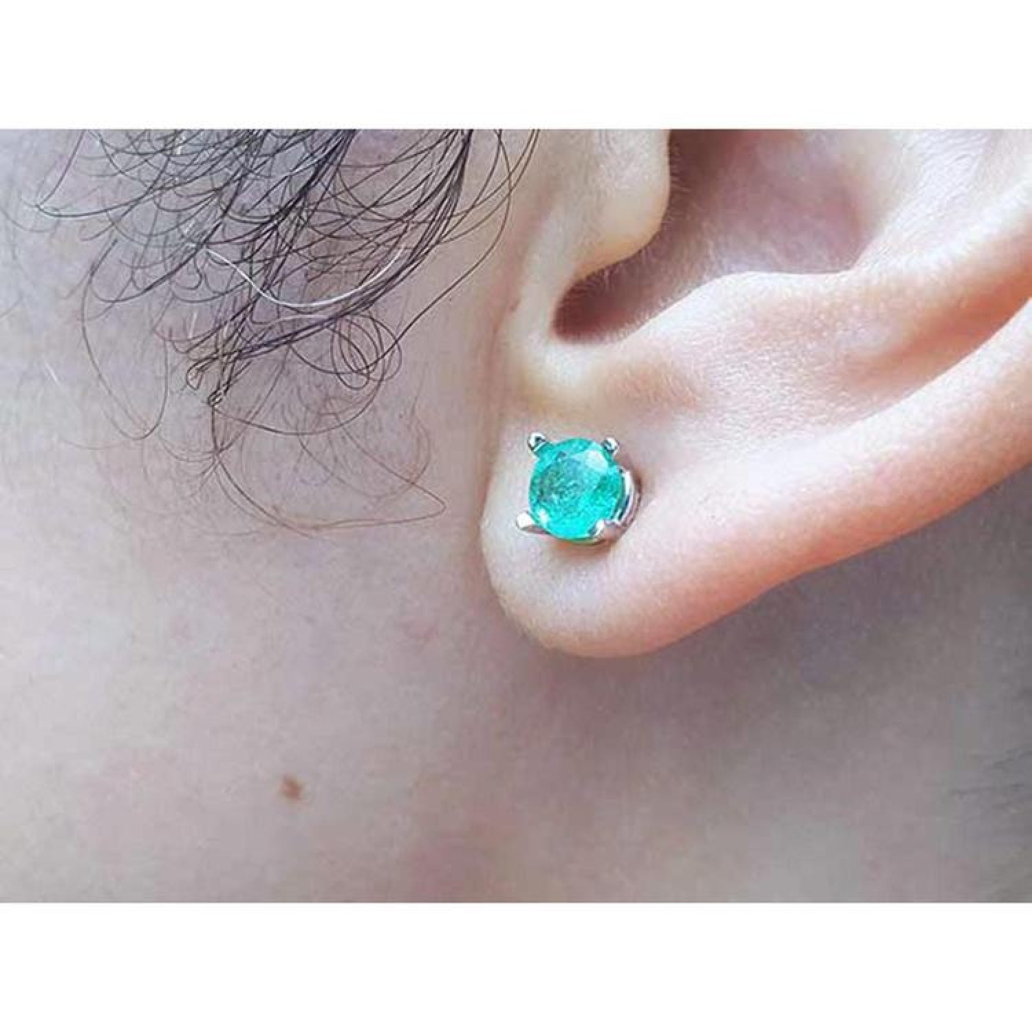 Round-cut Colombian emerald stud earring in 14k white gold, worn on an ear.
