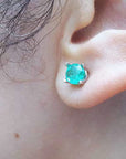 Close-up of an ear wearing a Colombian emerald stud earring.