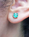 Close-up of an ear wearing a Colombian emerald stud earring with a blurred background