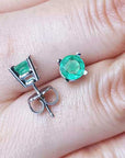 Colombian emerald stud earrings round cut on fingers.