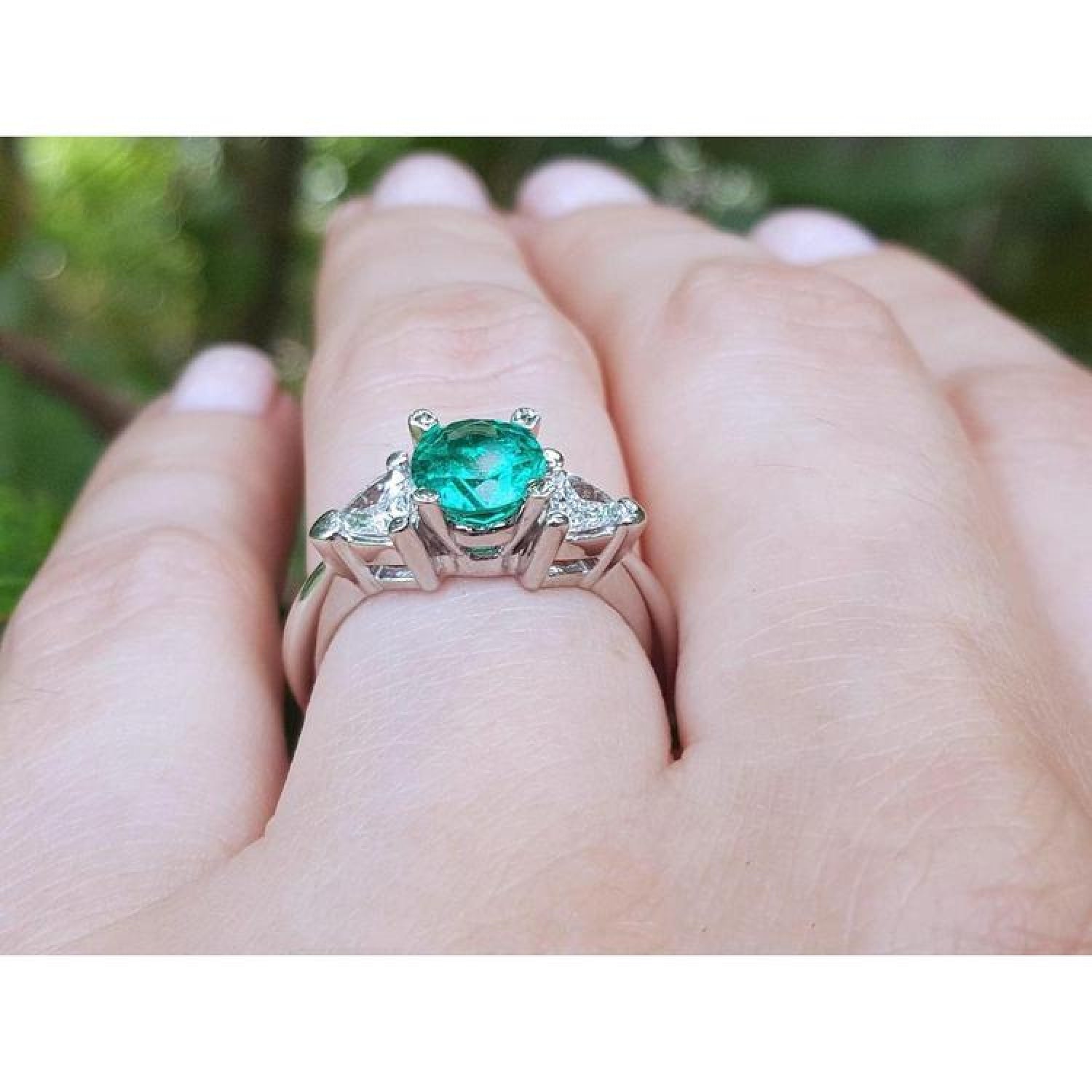 1.00 ct. round emerald ring with trillion side diamonds on a hand, 14K white gold.