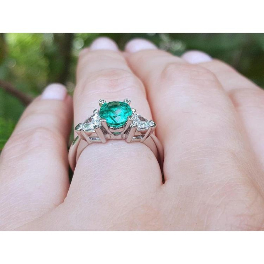 1.00 ct. round emerald ring with trillion side diamonds on a hand, 14K white gold.
