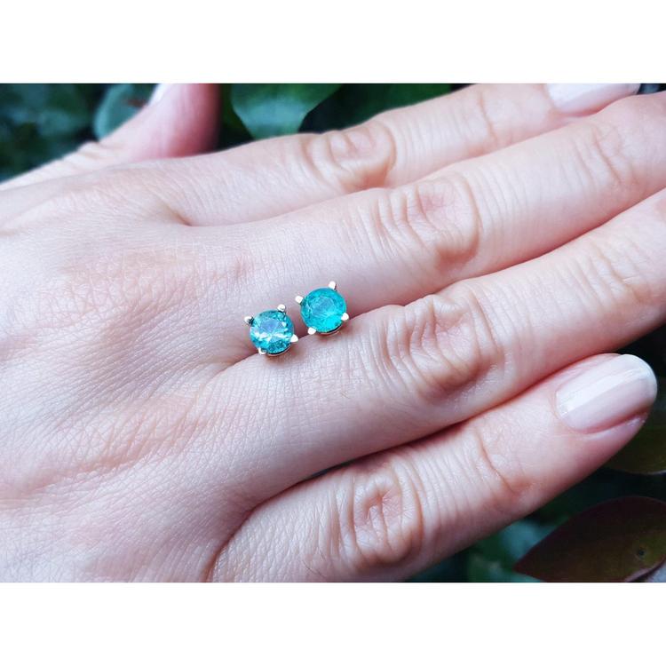 1.09 ct. natural Colombian emerald stud earrings in 14K gold basket settings with push backs, displayed on a hand.