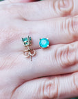 A pair of 14k yellow gold emerald stud earrings round cut and push backs on a hand.