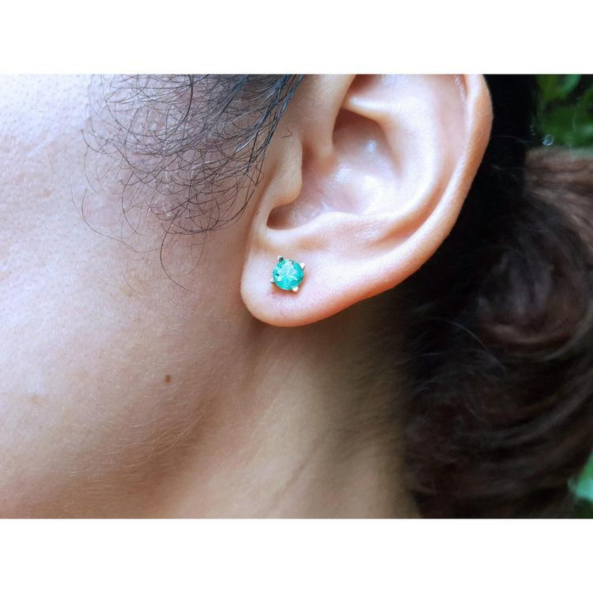 1.09 ct. round natural Colombian emerald stud earring in 14K gold basket setting on an ear.