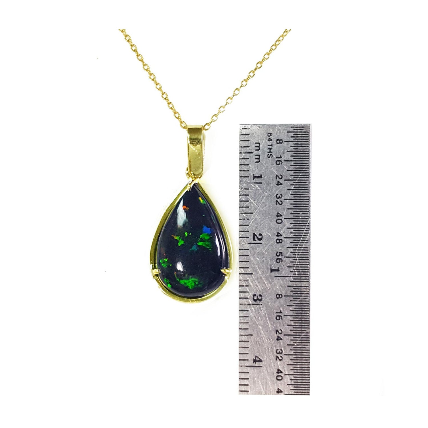Teardrop-shaped black opal pendant on a gold chain with a ruler for scale.