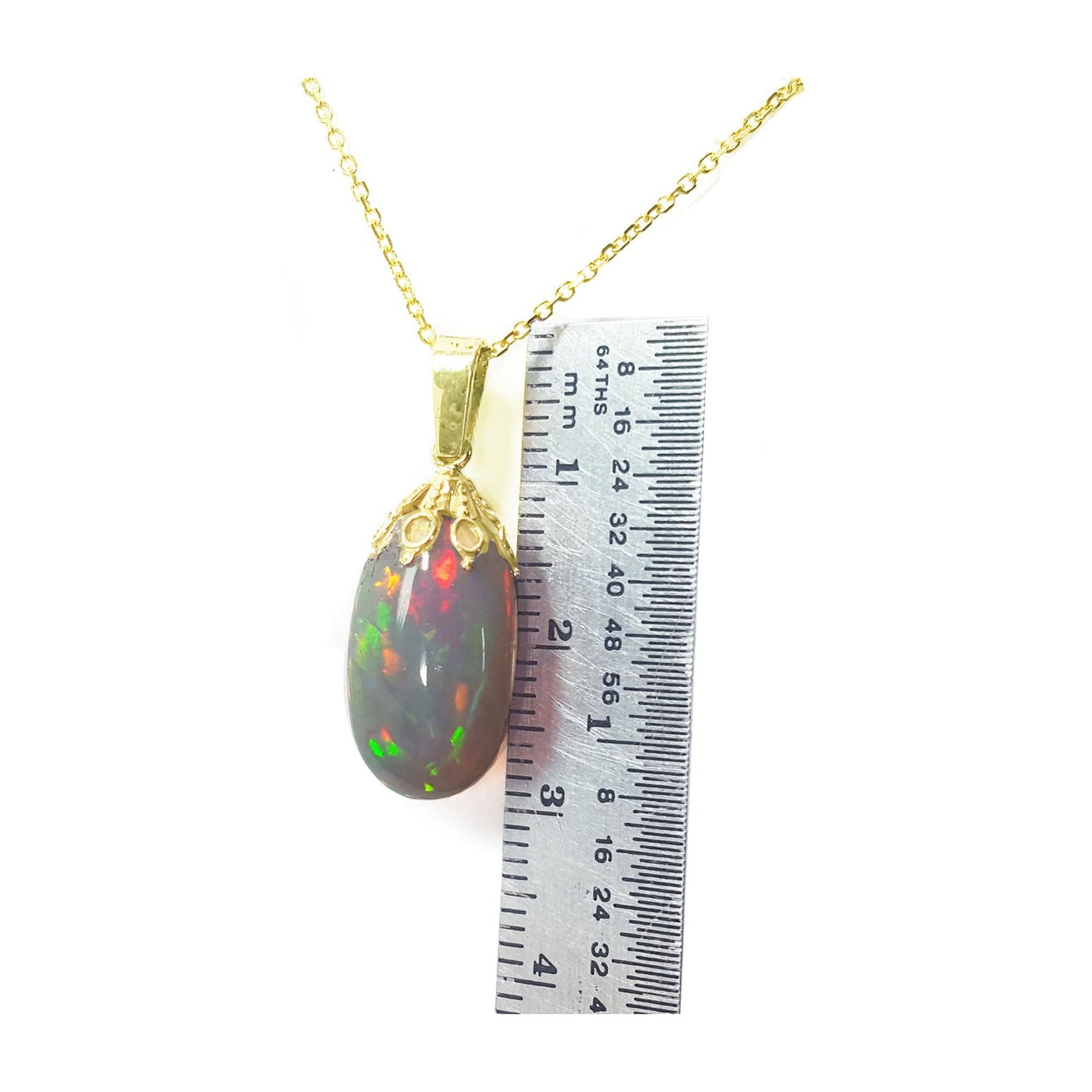 Opal pendant necklace with gold chain on a white background, accompanied by a ruler for scale.