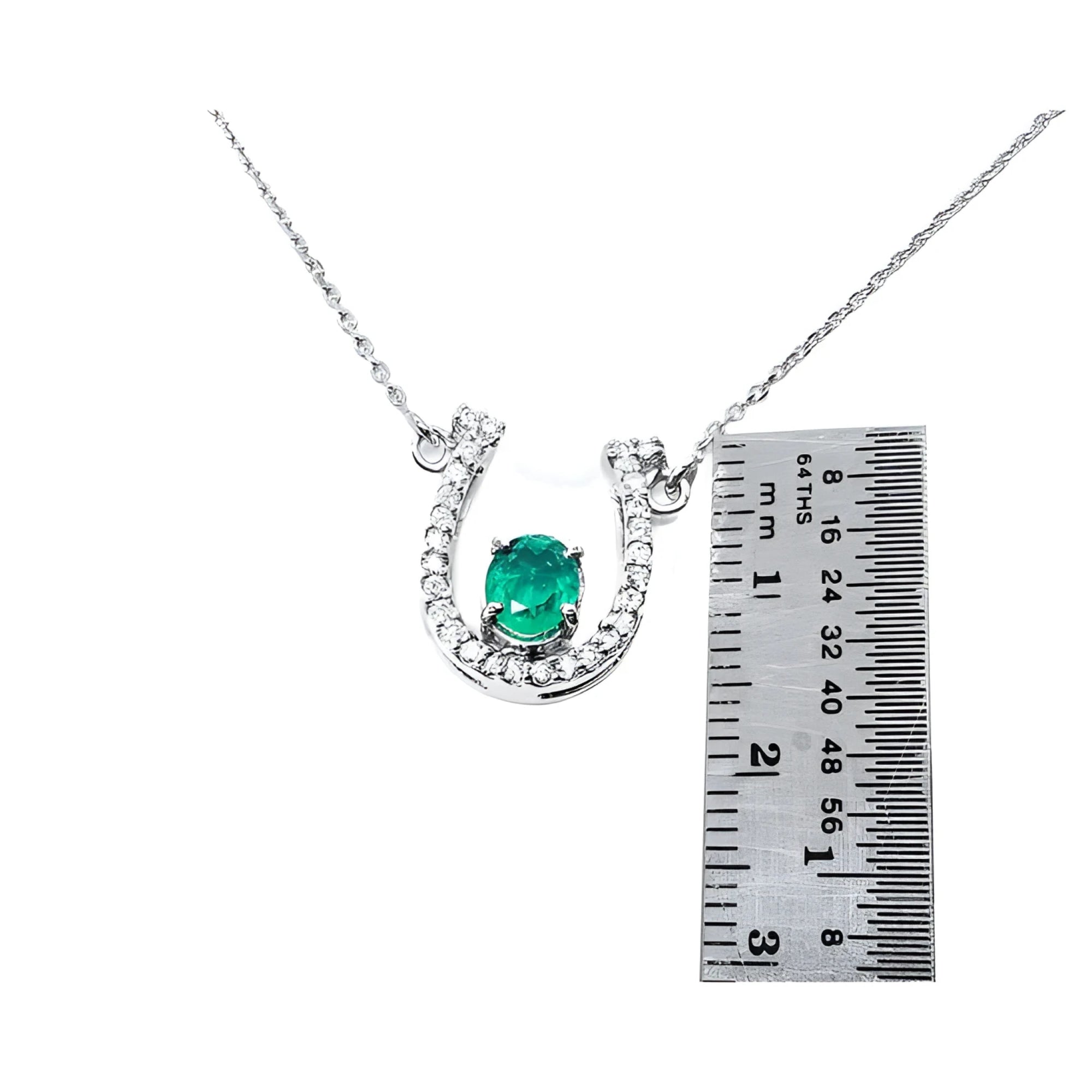 14K white gold horseshoe necklace with oval emerald and diamond accents, shown with ruler for size.