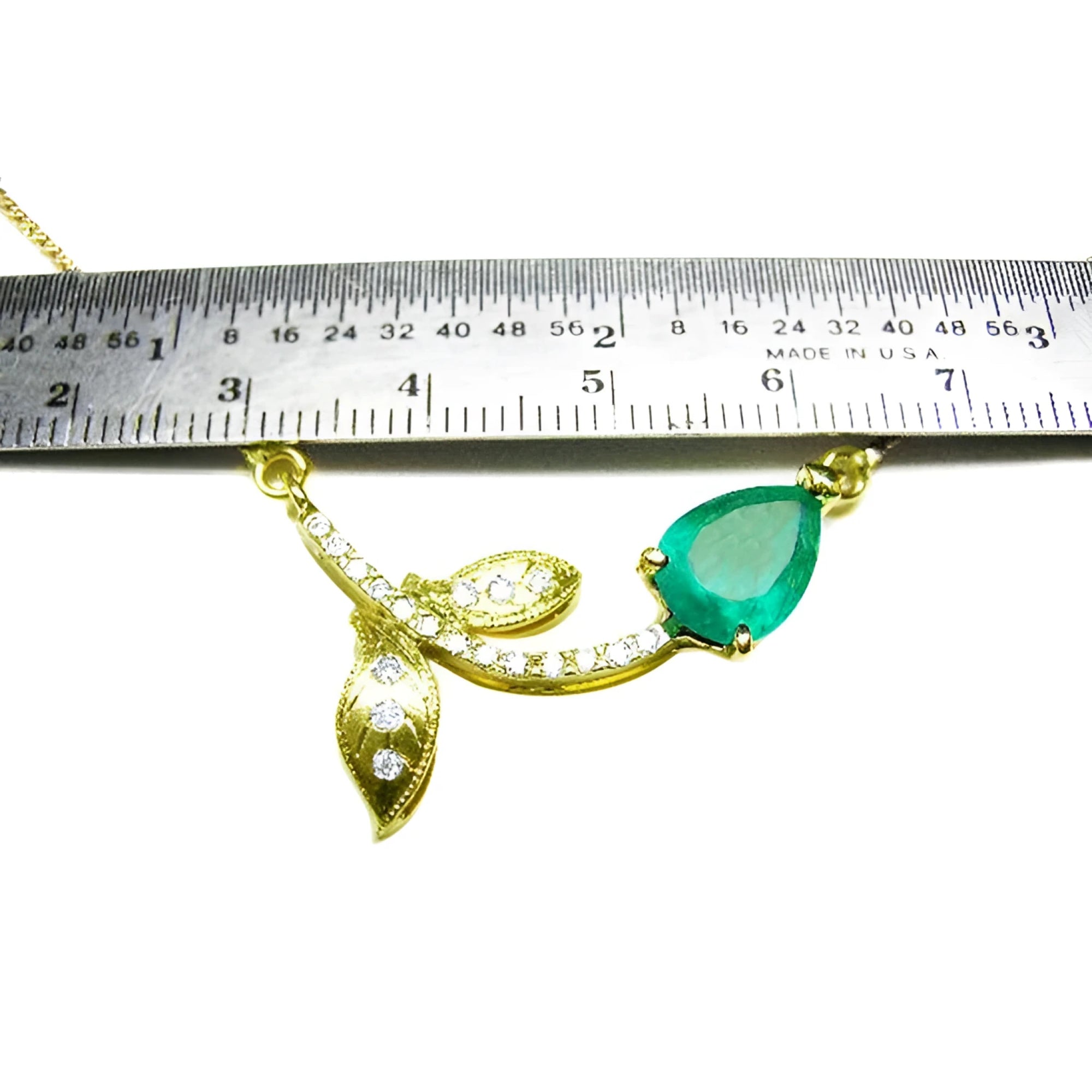 14K yellow gold twig necklace with a pear-cut Colombian emerald and diamond accents, measured by a ruler.