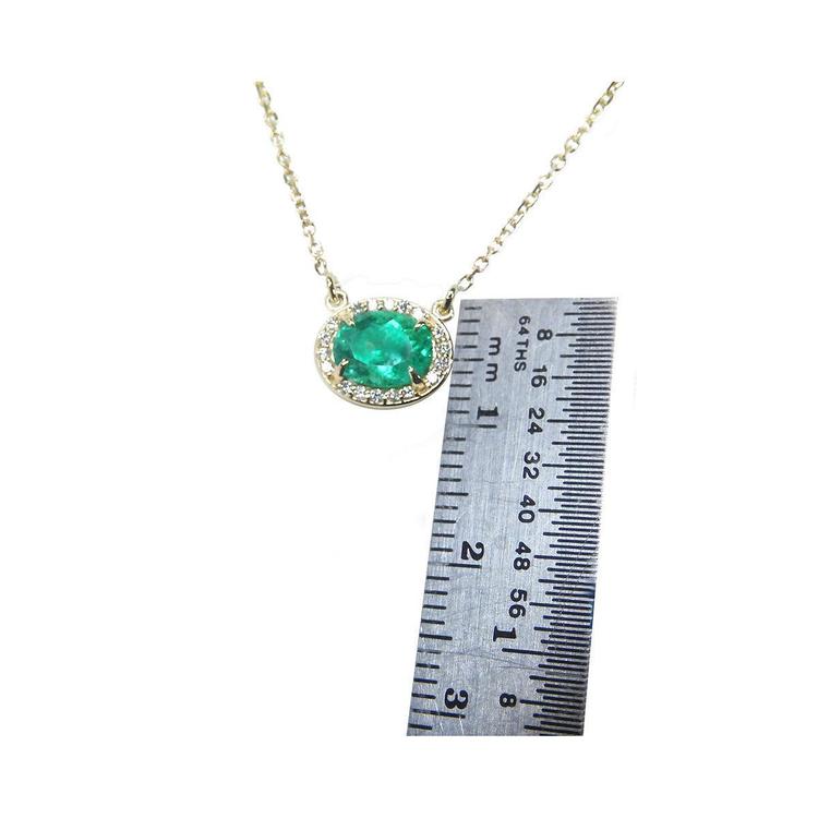 0.90 carat oval Muzo emerald necklace in 14K yellow gold, shown with a ruler for scale.