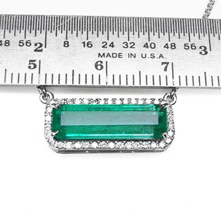 18K white gold Colombian emerald necklace with halo diamonds, East-West rectangular design, measured by a ruler.