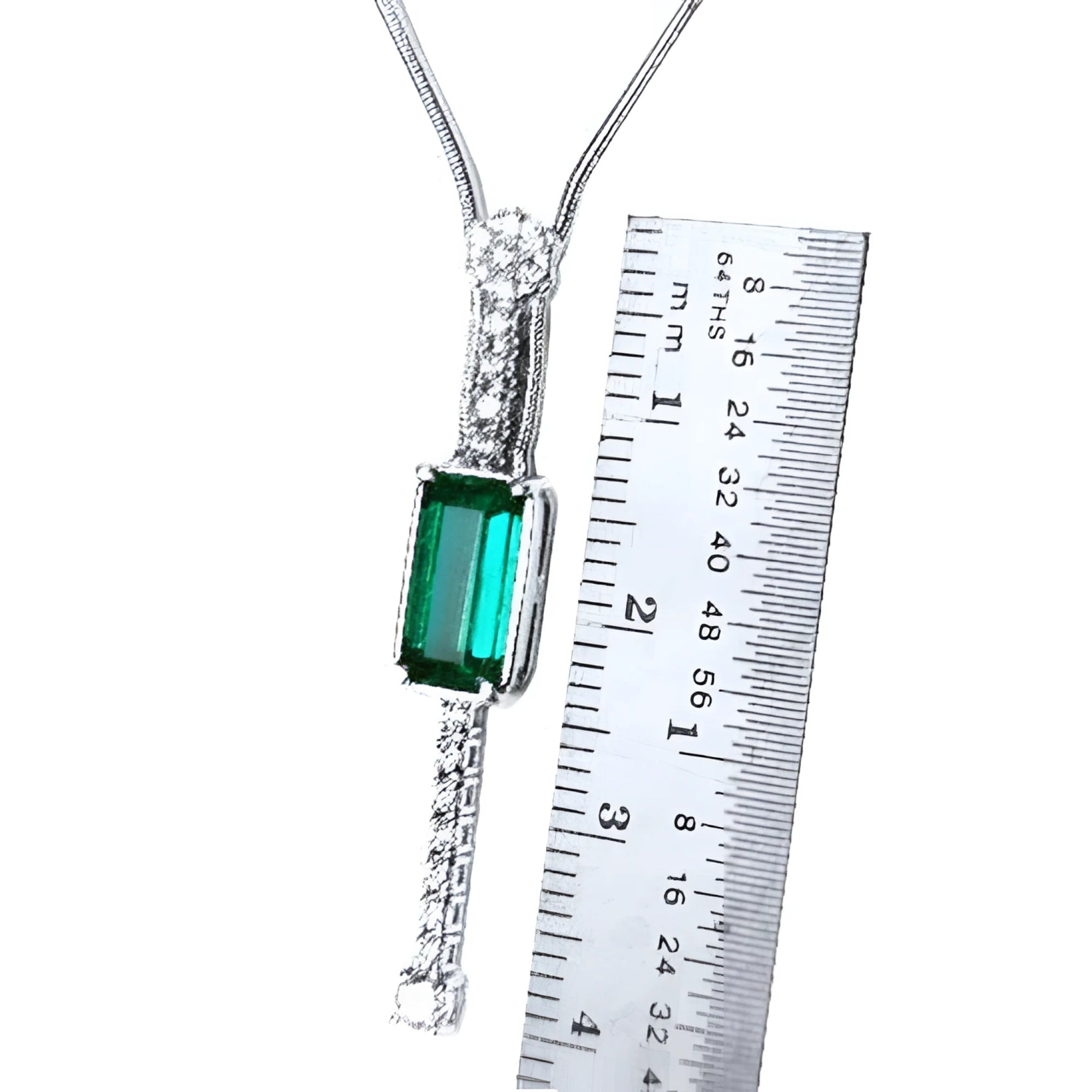 White gold necklace with a rectangular Colombian emerald and diamond accents, shown next to a ruler.