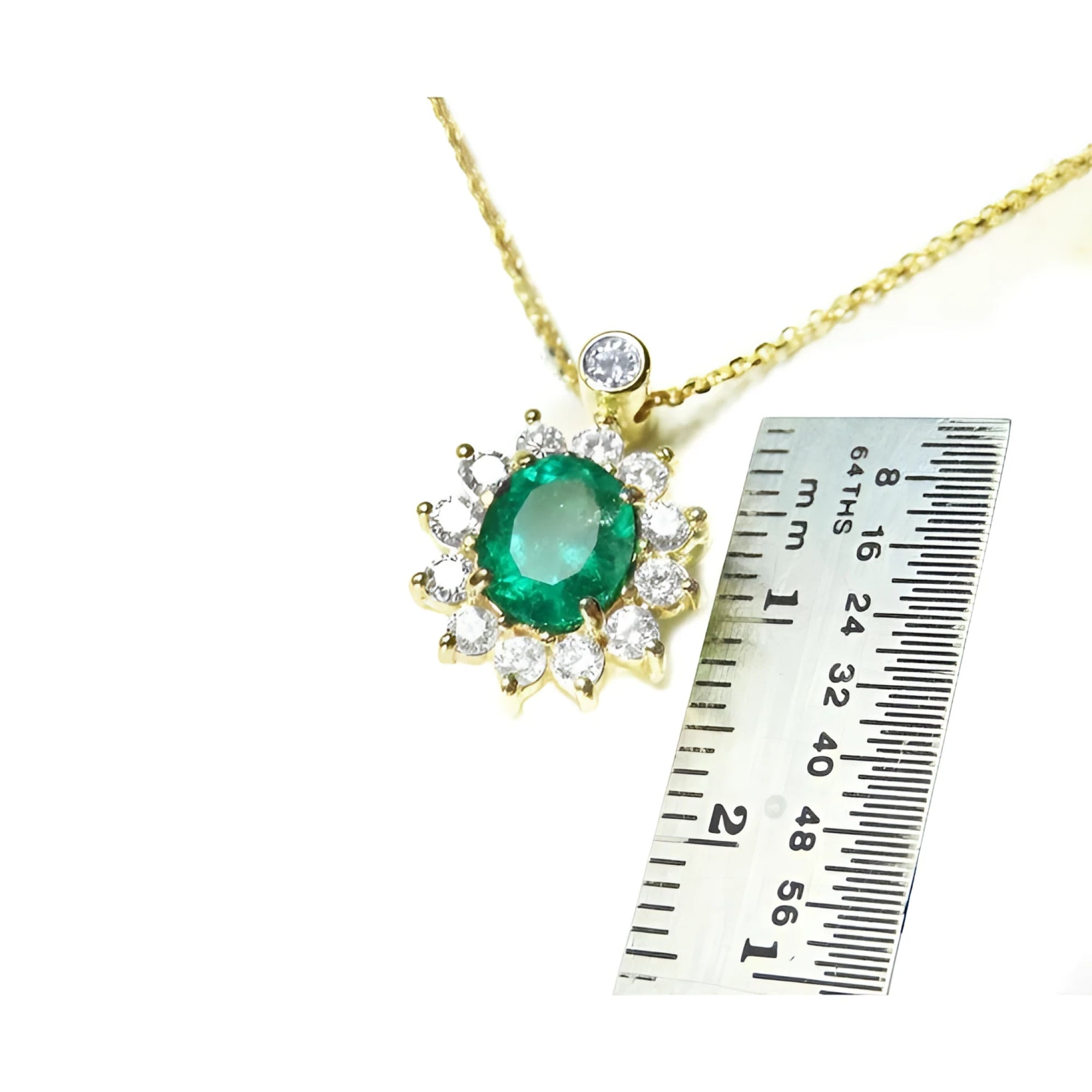 Oval cut emerald and natural diamond cluster necklace in 14K yellow gold, shown with a ruler for scale.