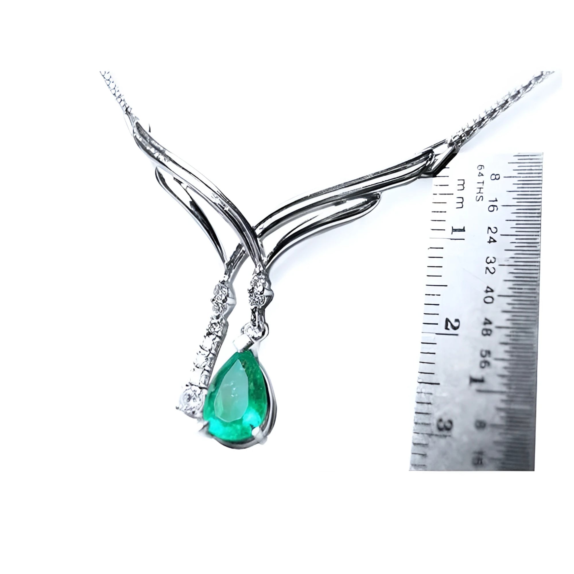 14K white gold necklace with a pear-shaped emerald and diamond chevron design, shown with a ruler.