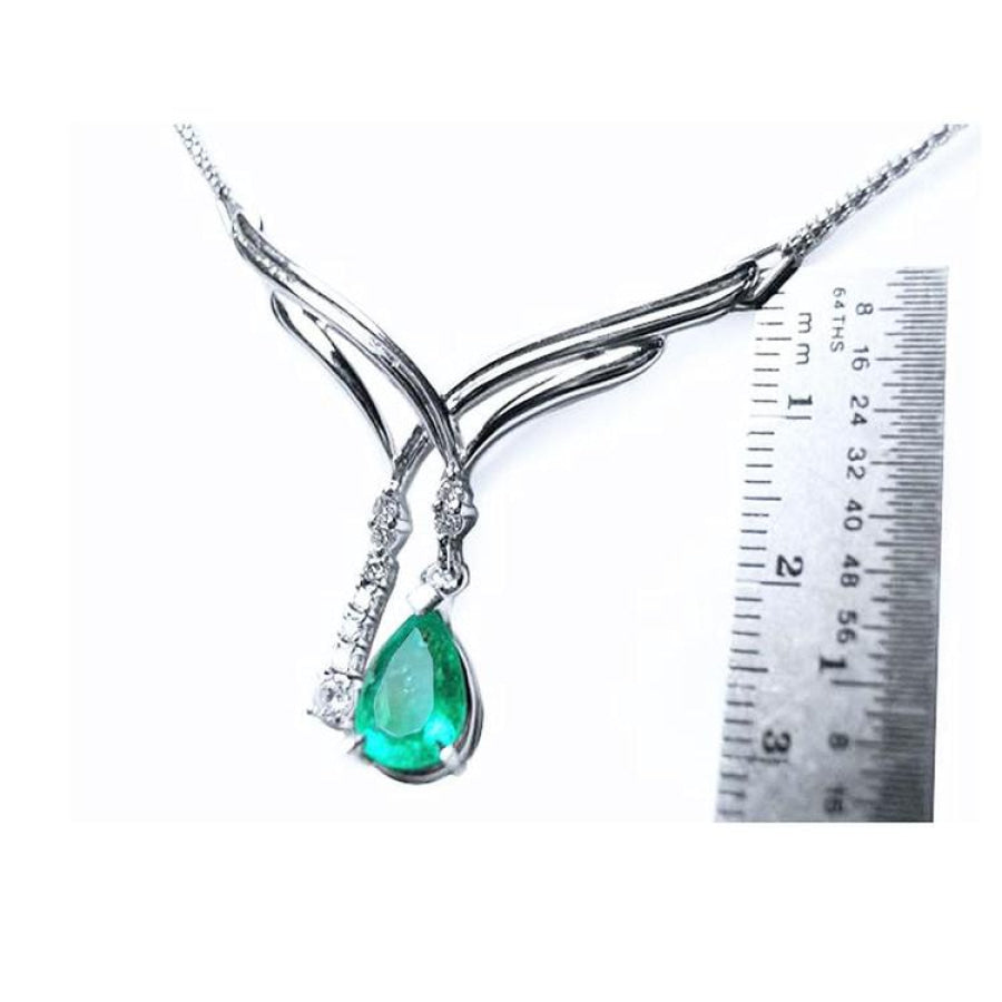 14K white gold necklace with a pear-shaped emerald and diamond chevron design, shown with a ruler.
