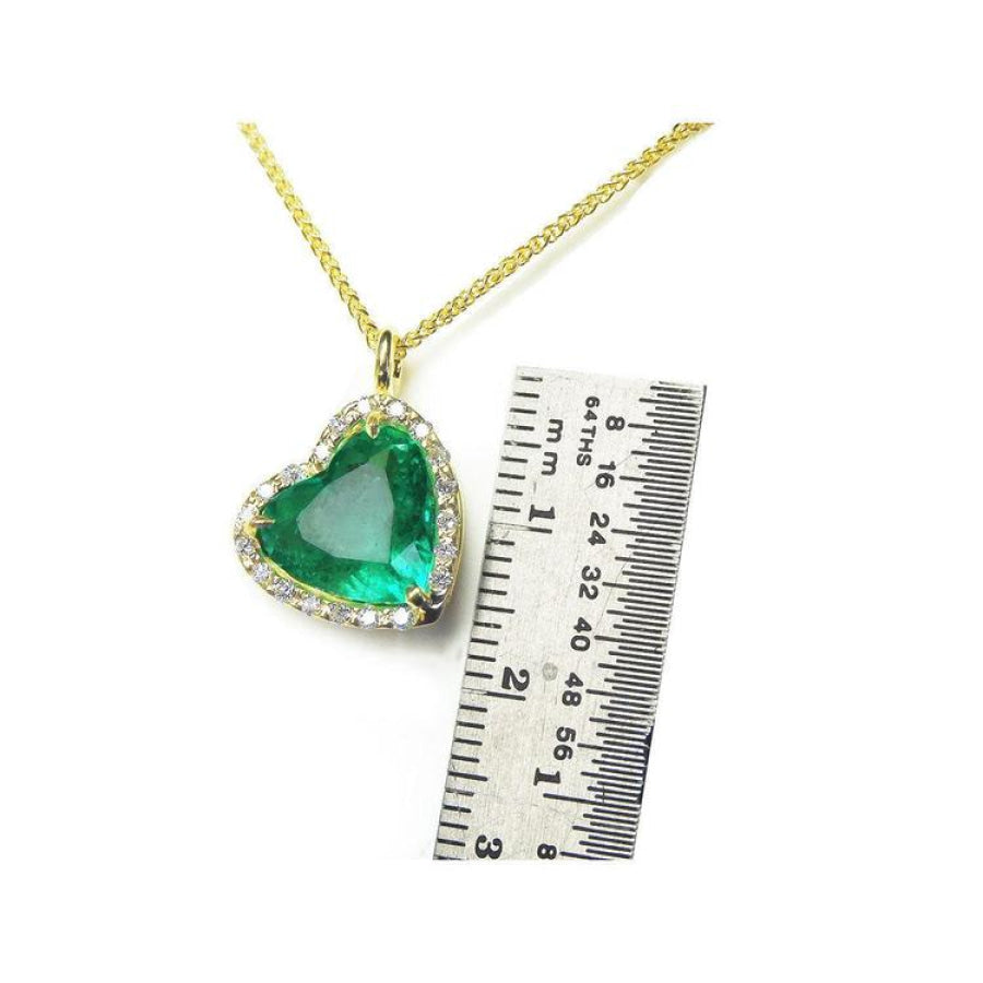 Tilted heart emerald necklace with halo diamonds on an 18K gold chain, shown with a ruler for scale.