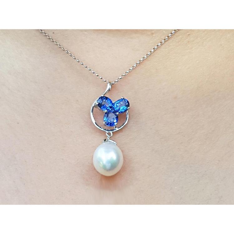 Pearl and blue sapphire cluster necklace on a person's neck