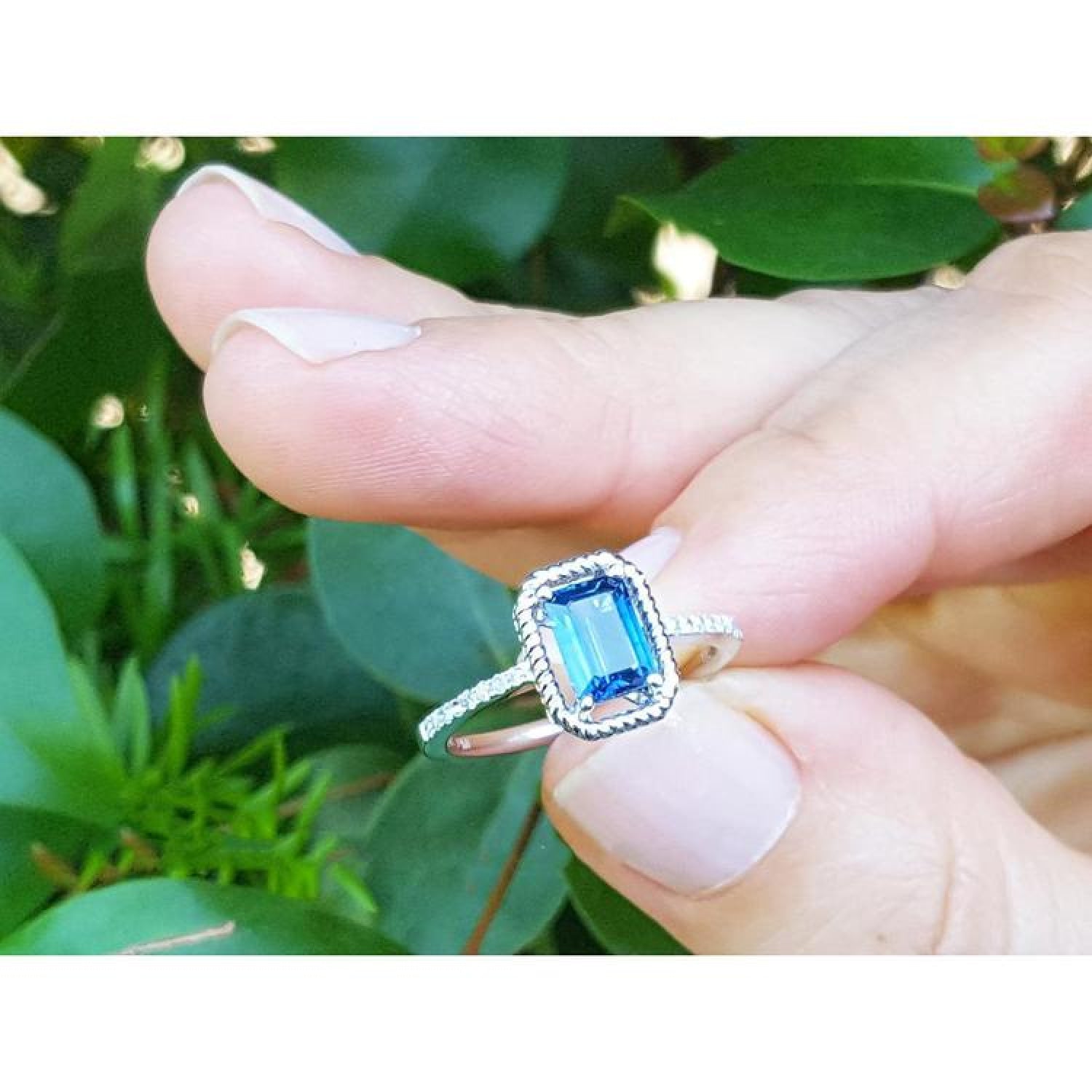 1.03 ct emerald cut blue sapphire solitaire ring in 14K white gold with rope frame and diamond shank.