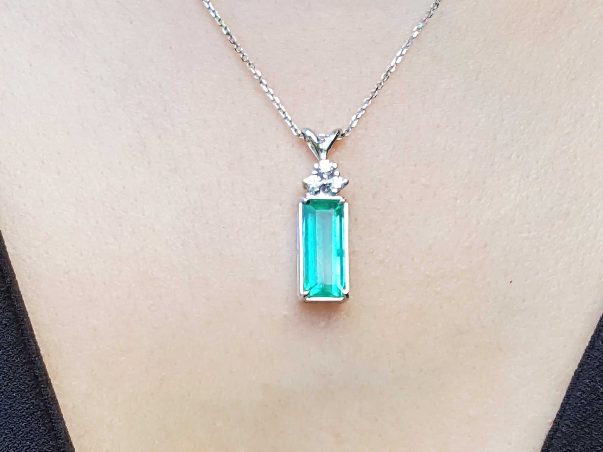 A natural emerald pendant on a white gold chain dangling of a woman&#39;s neck