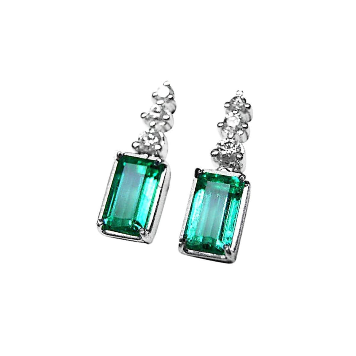 Pair of earrings with natural emeralds and top diamond accents on a left side profile