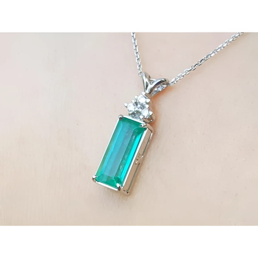 Emerald pendant with accent diamonds in 14K white gold on a delicate chain.