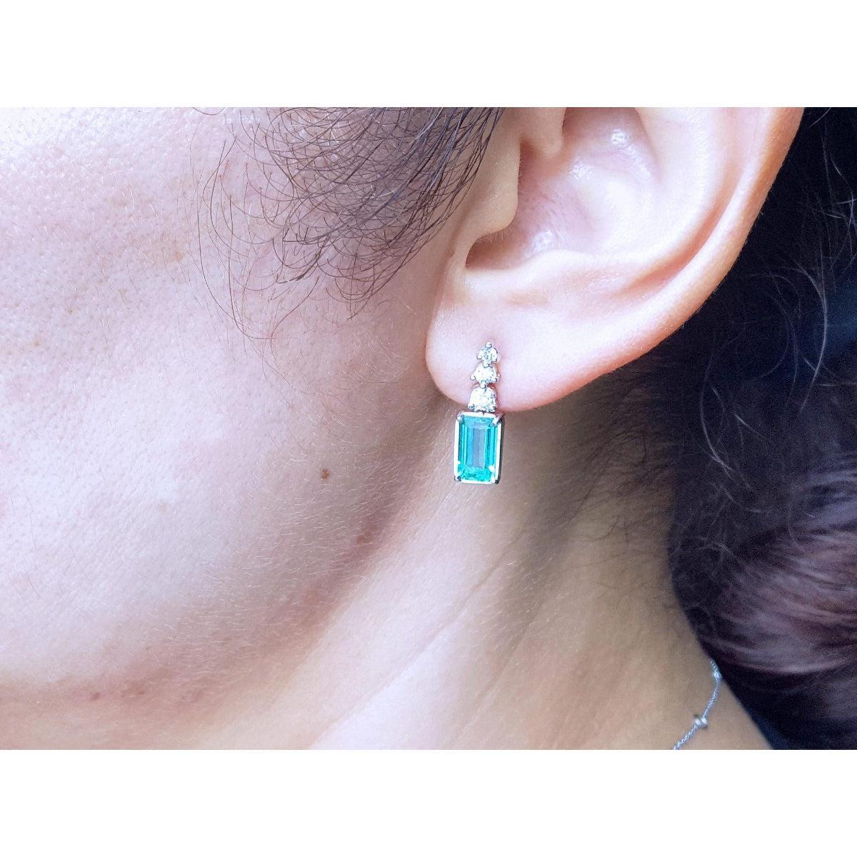 Close-up of an ear wearing a natural emerald-cut earring.