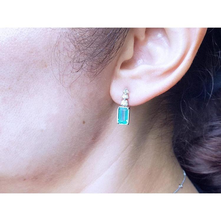 Close-up of an ear wearing a natural emerald-cut earring.