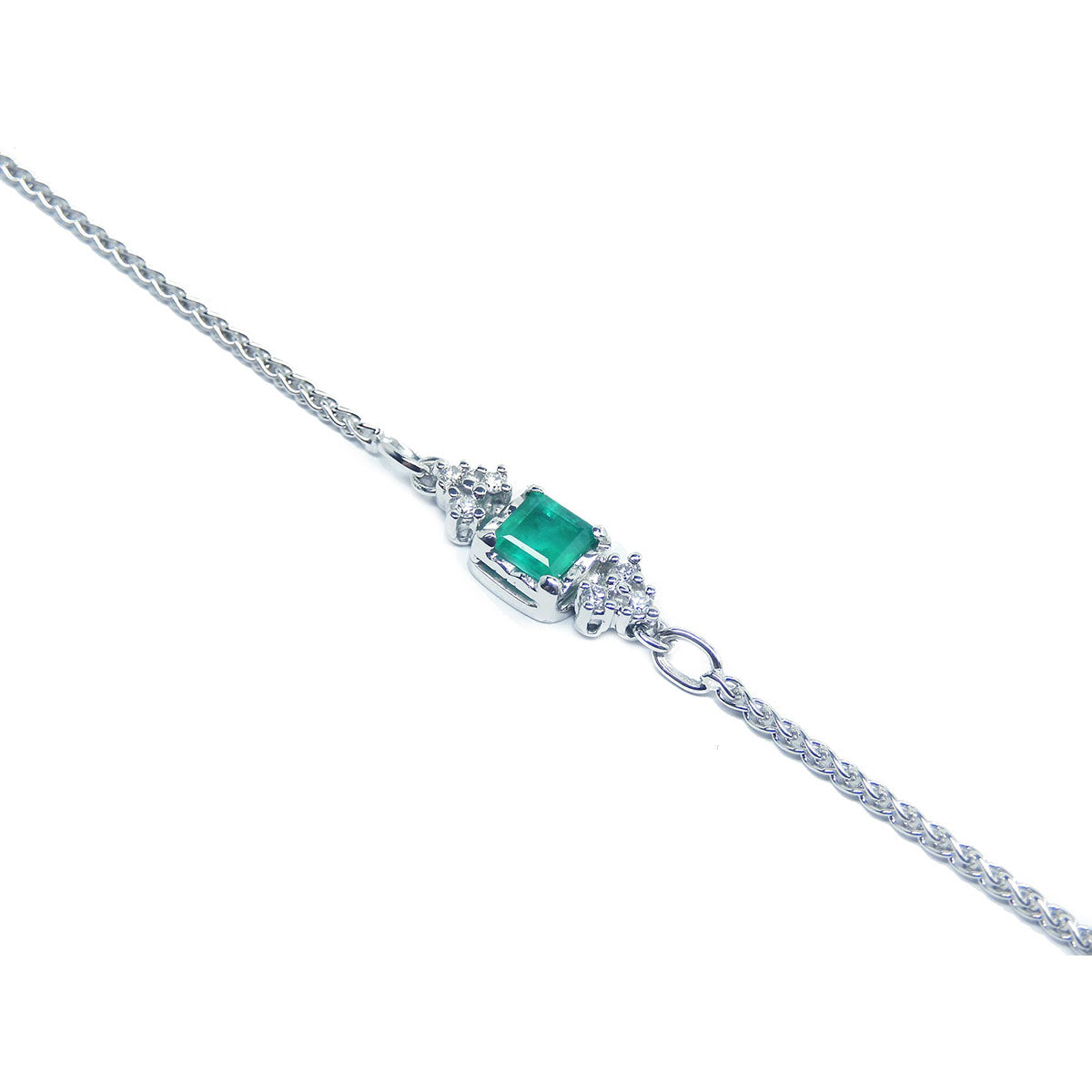 The side profile of a white gold emerald and diamond bracelet.