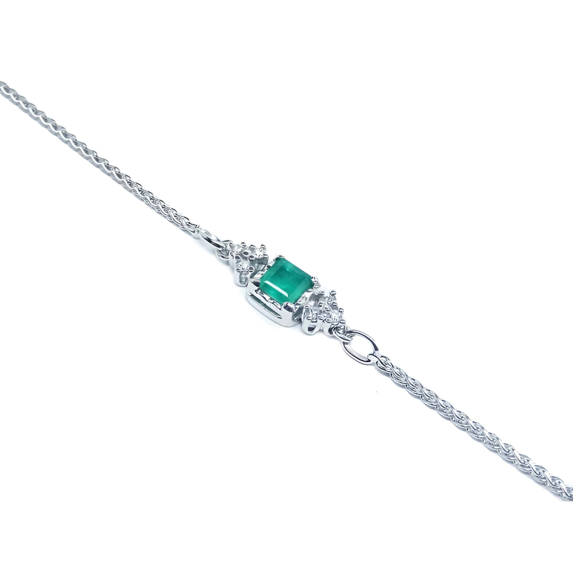 14K white gold bracelet with a central emerald-cut Colombian emerald and diamond accents.
