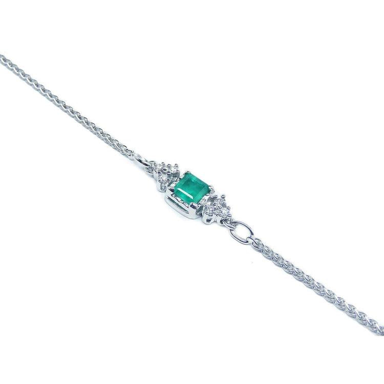 14K white gold bracelet with a central emerald-cut Colombian emerald and diamond accents.