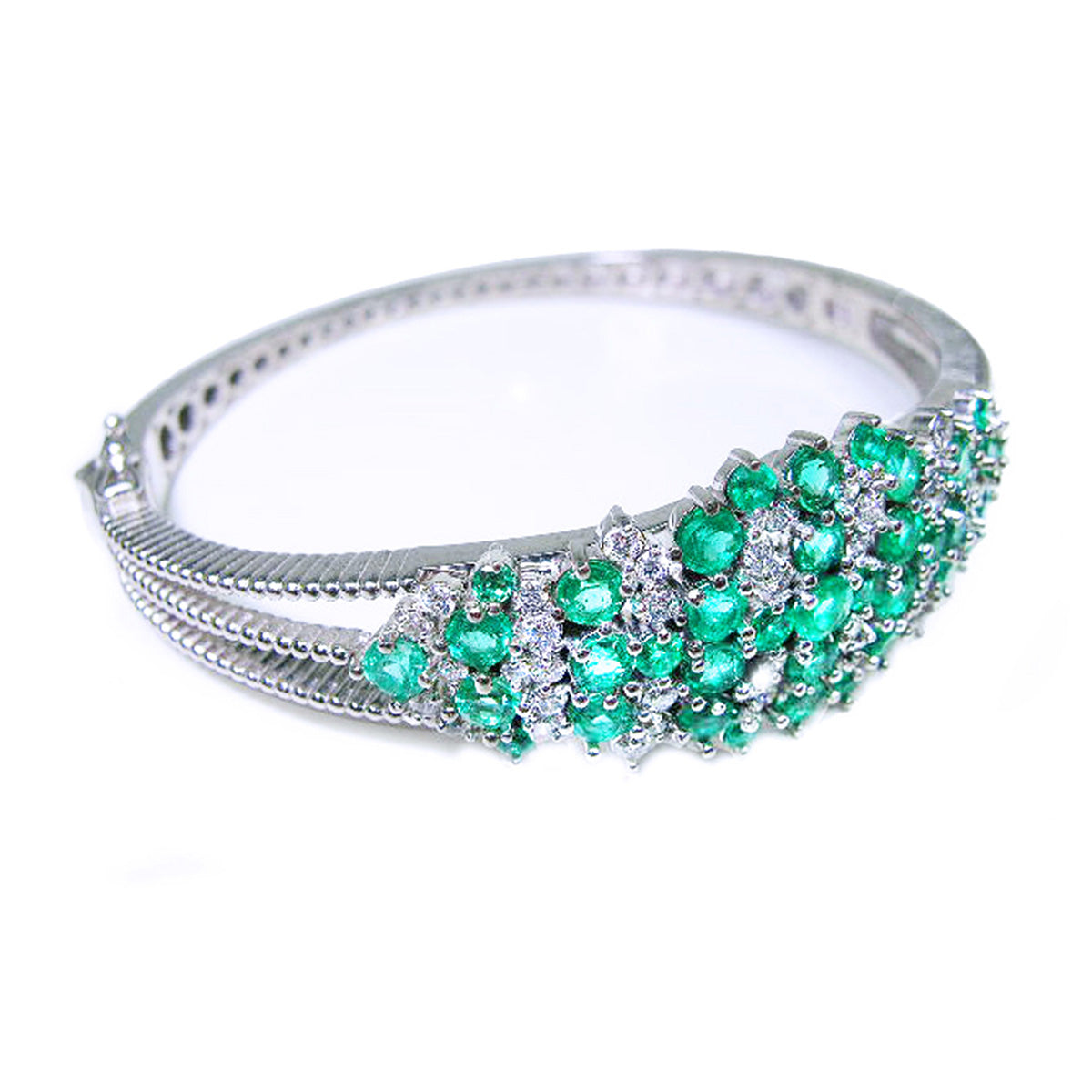 Right side profile view of a white gold bangle bracelet with round natural emeralds and diamonds on a white background.