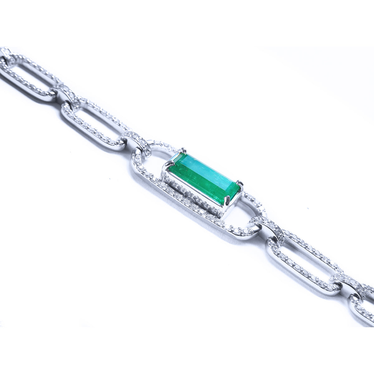 The side profile of a paperclip style bracelet with an emerald-cut natural emerald on a white background.