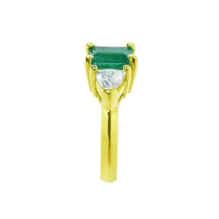 18K gold ring with a rectangular emerald center stone and trillion side diamonds.