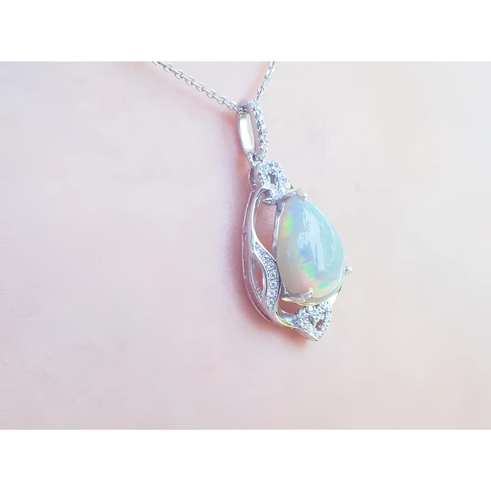 Pear-shaped rainbow Welo Ethiopian Opal pendant in 925 sterling silver with cubic zirconia accents.