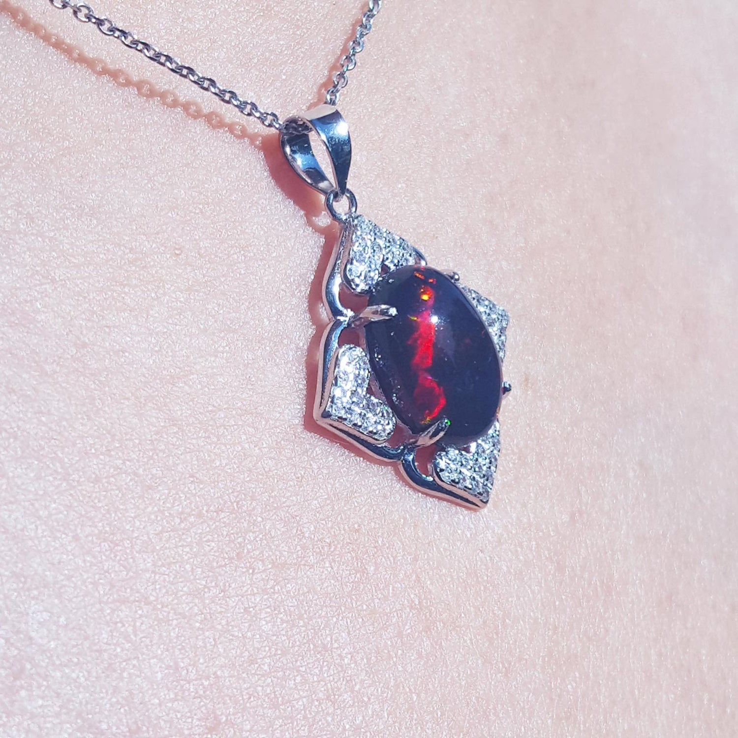 Silver pendant with a black Ethiopian opal on a light pink fabric background