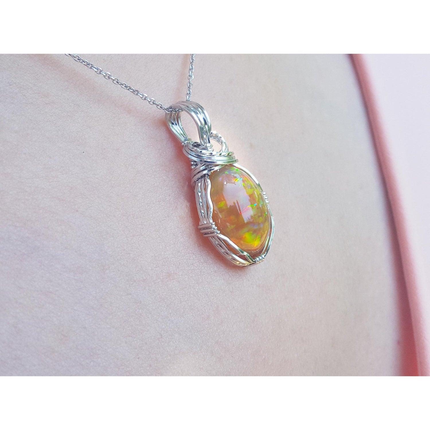 Opal pendant necklace on a light pink skin background.