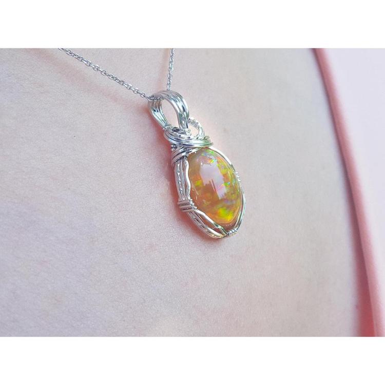 Ethiopian opal pendant with vibrant play of colors and brown pinpoint fire, set in a silver wire wrap.