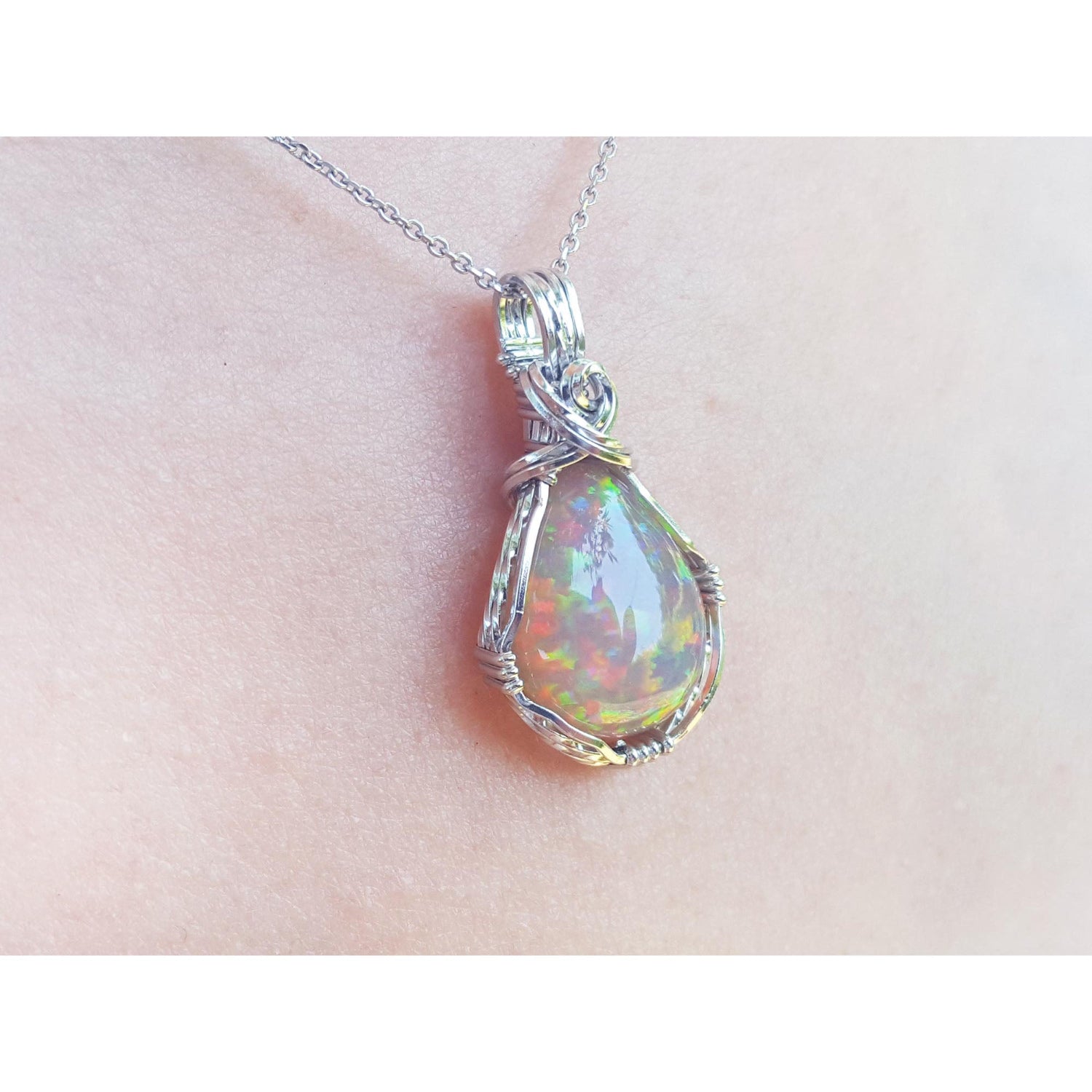 Opal pendant silver necklace on a person&#39;s neck with a white background.