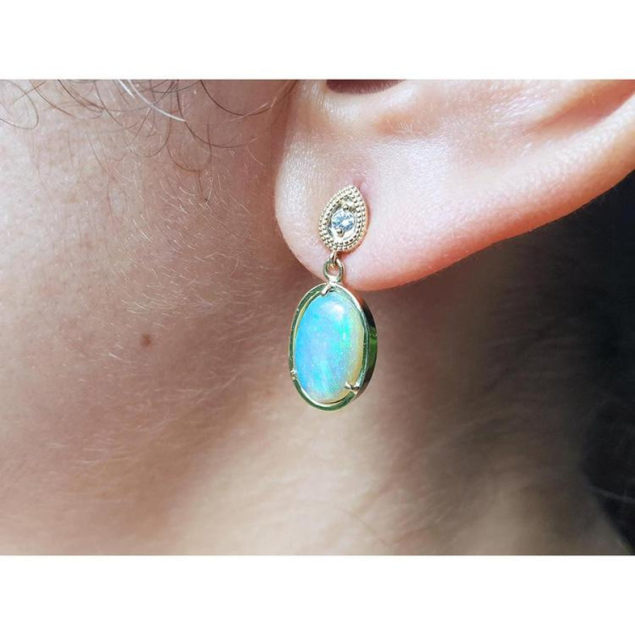 Solid Australian opal earrings with bluish-green play of color, dangling diamond studs, 14K yellow gold.