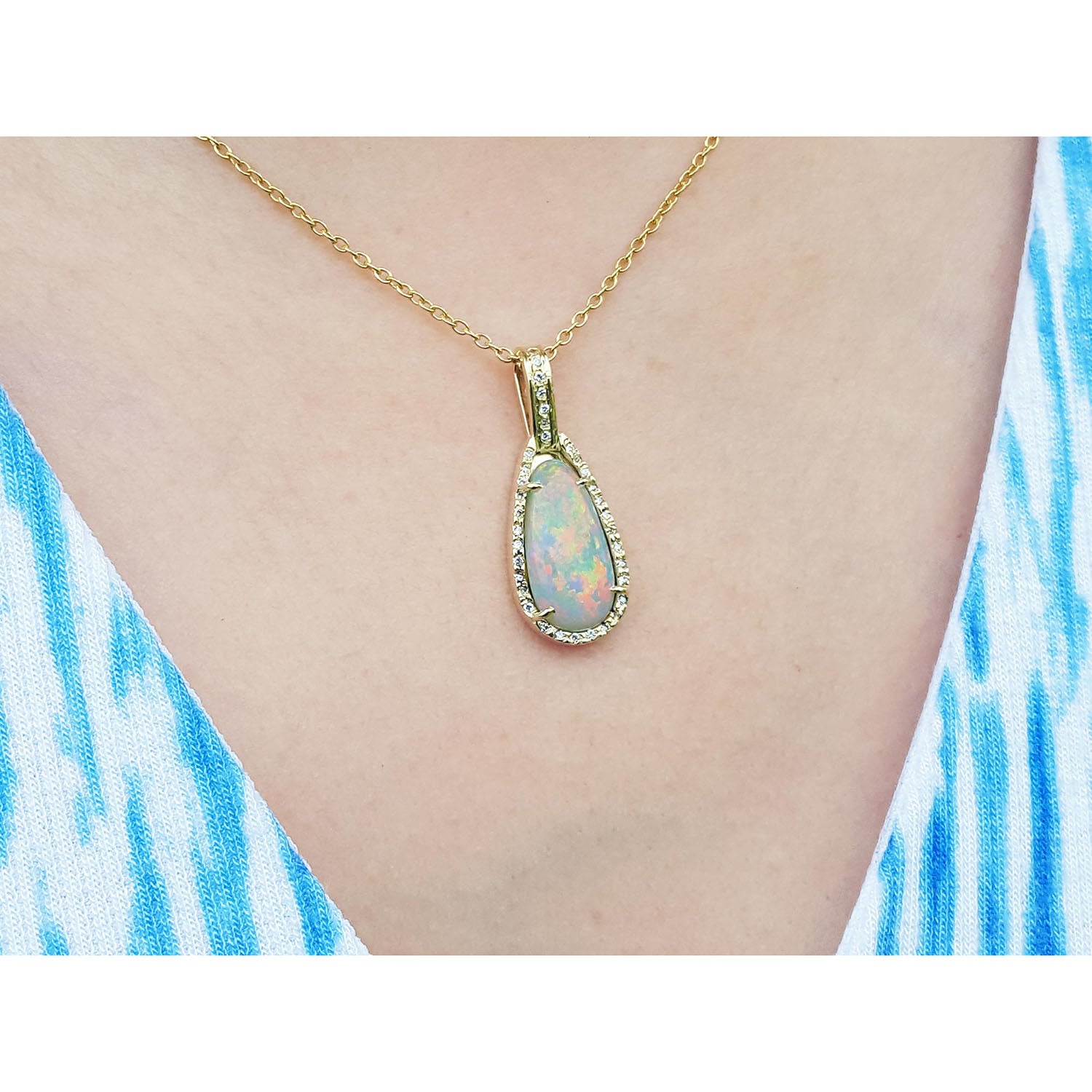 Opal pendant necklace on a person wearing a blue and white striped top.