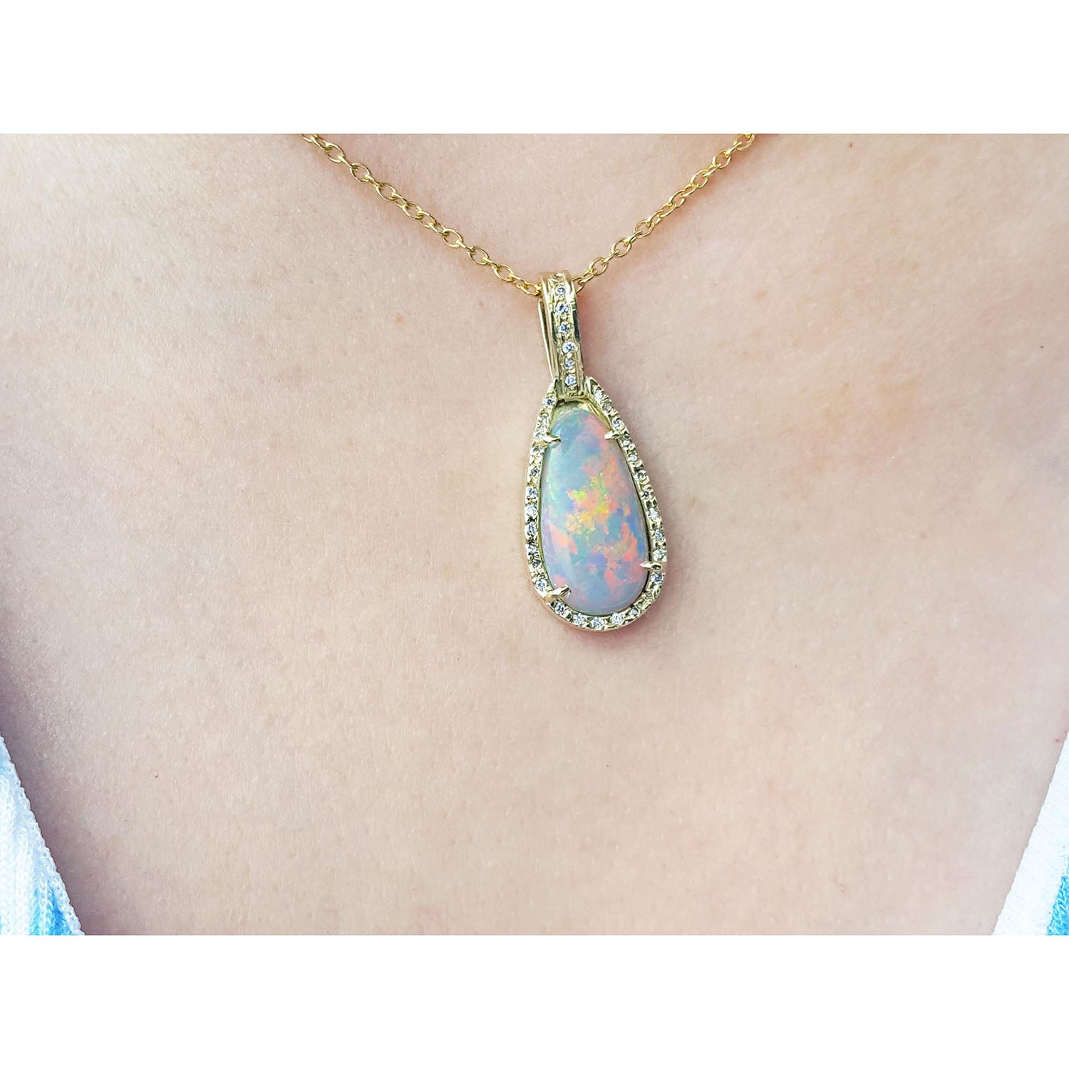 Opal pendant necklace on a gold chain worn by a person