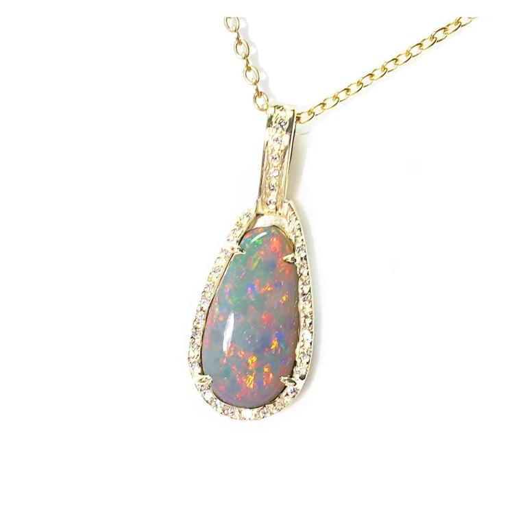 Opal pendant necklace on a gold chain displaying the topside with a gold and diamonds frame.