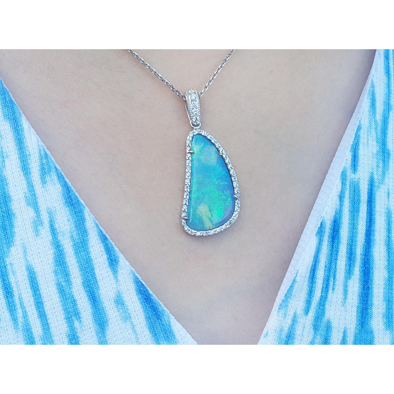 Teardrop-shaped opal pendant on a white gold chain on a person&#39;s neck.