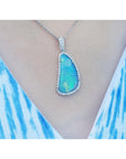 Teardrop-shaped opal pendant on a white gold chain on a person's neck.