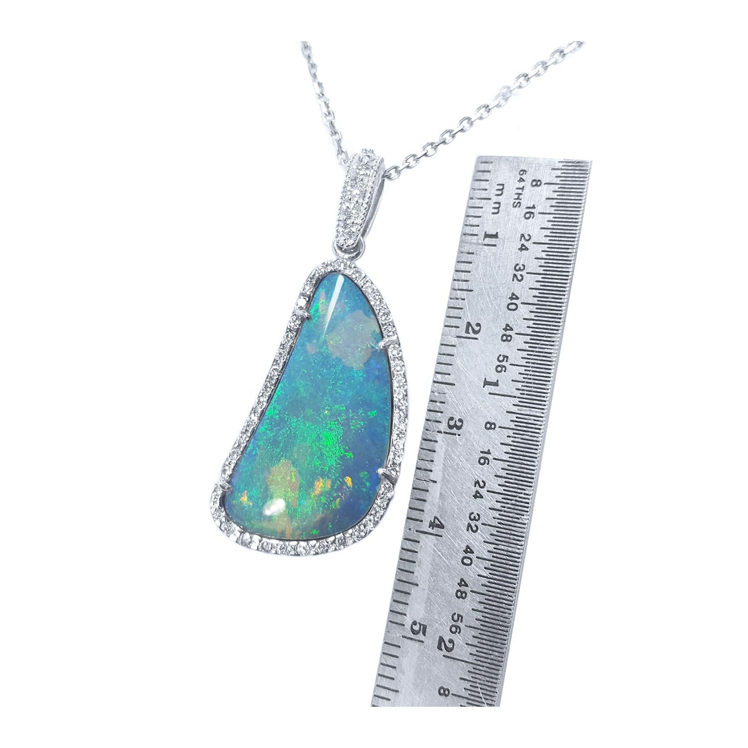 A genuine solid Australian opal pendant necklace with a ruler for scale on a white background.