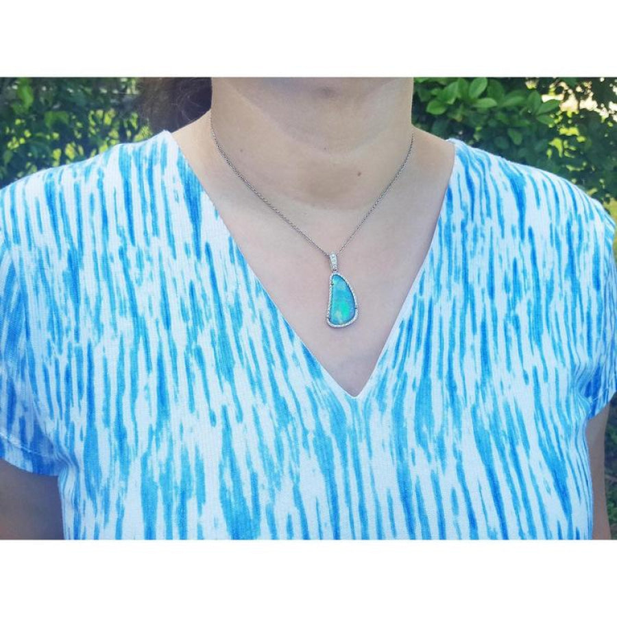 Australian opal pendant with blue-green play of color, halo diamonds, 18K white gold, worn on a woman.