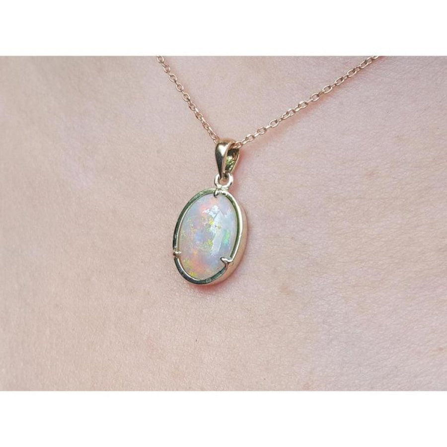 1.92 ct. oval white opal pendant in 14k yellow gold on a delicate chain, worn on a person.